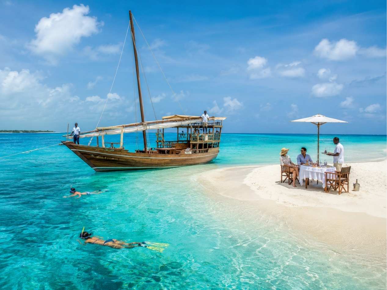Traditional wooden dhow sailing on turquoise waters at sunset